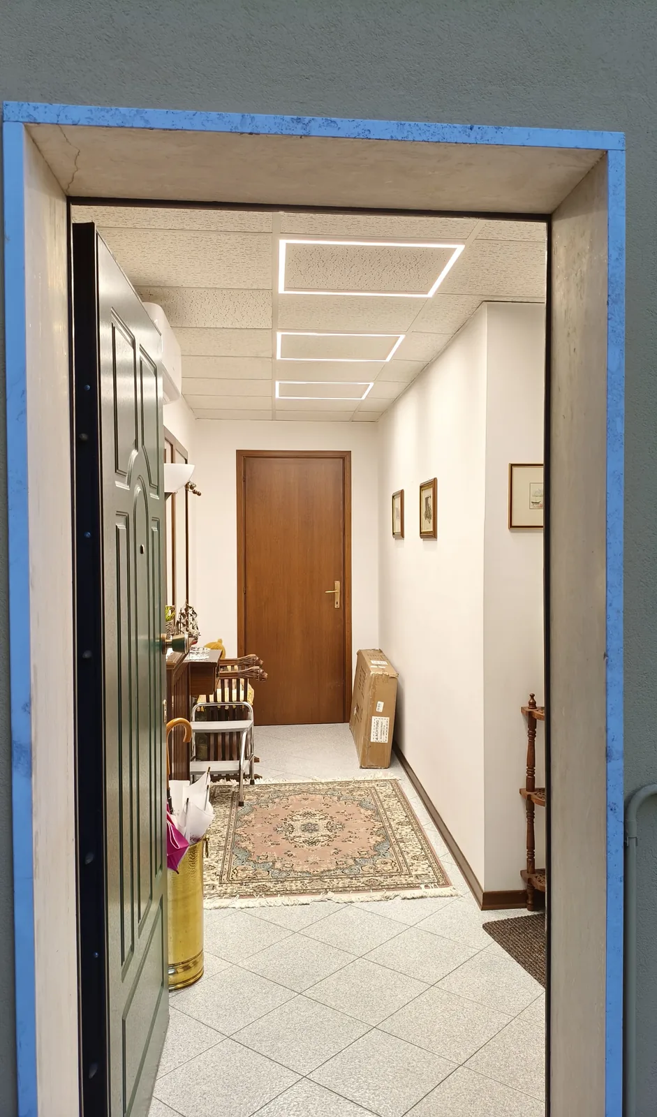Corridoio d'ingresso con tre cornici luminose LED rettangolari integrate nel controsoffitto a quadrotti