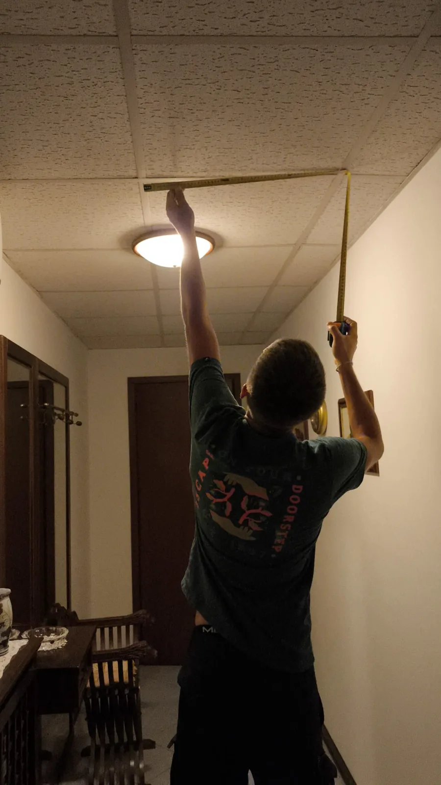 Corridoio con controsoffitto a quadrotti illuminato da una sola plafoniera tonda, durante il rilievo misure