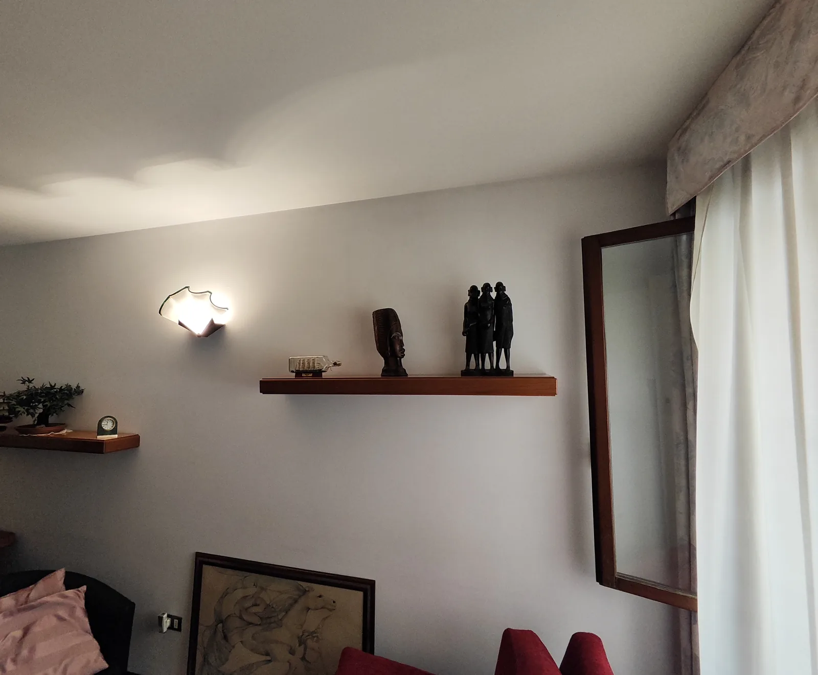 Studio prima dell'intervento: una sola applique a parete e luce scarsa sulle mensole